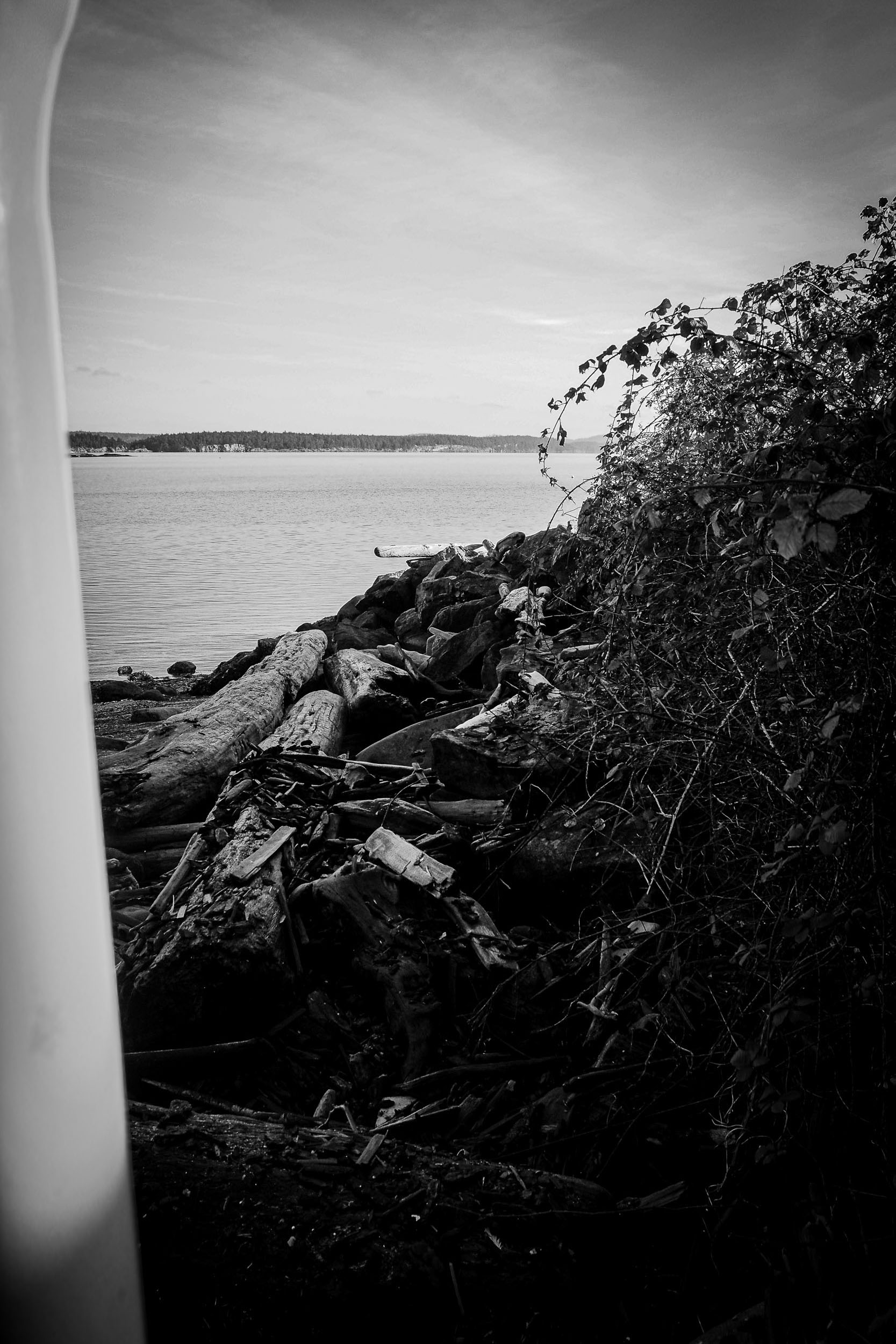 A rocky shoreline reaches into open water below a pale horizon.