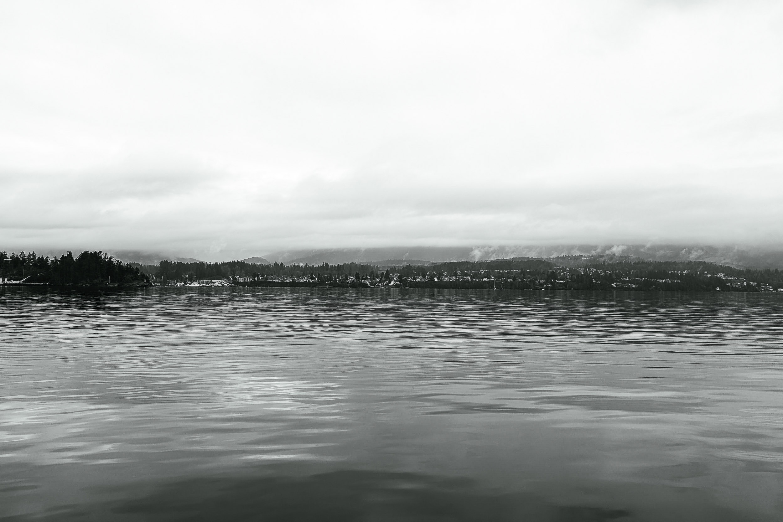 A quiet expanse of water meets a low, hazy shoreline.