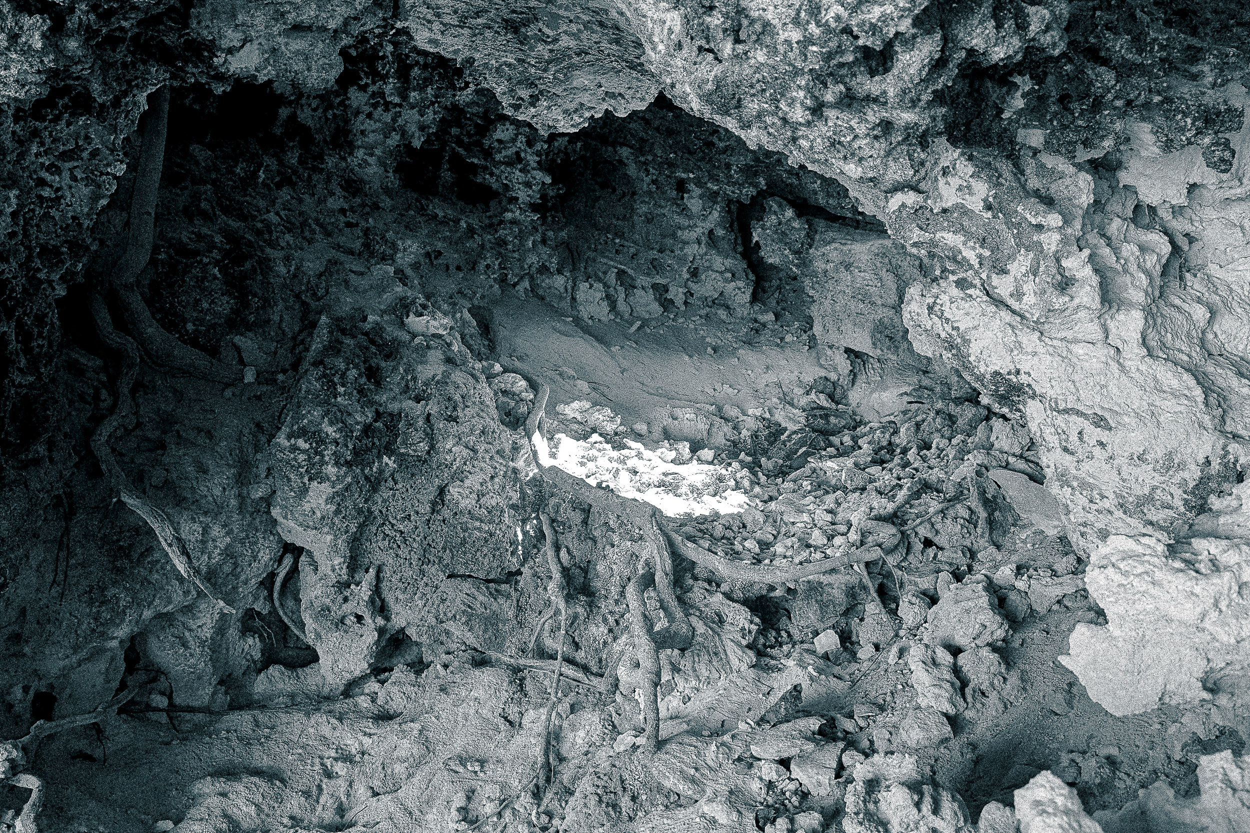 A pale rock formation rises from dark, textured ground.