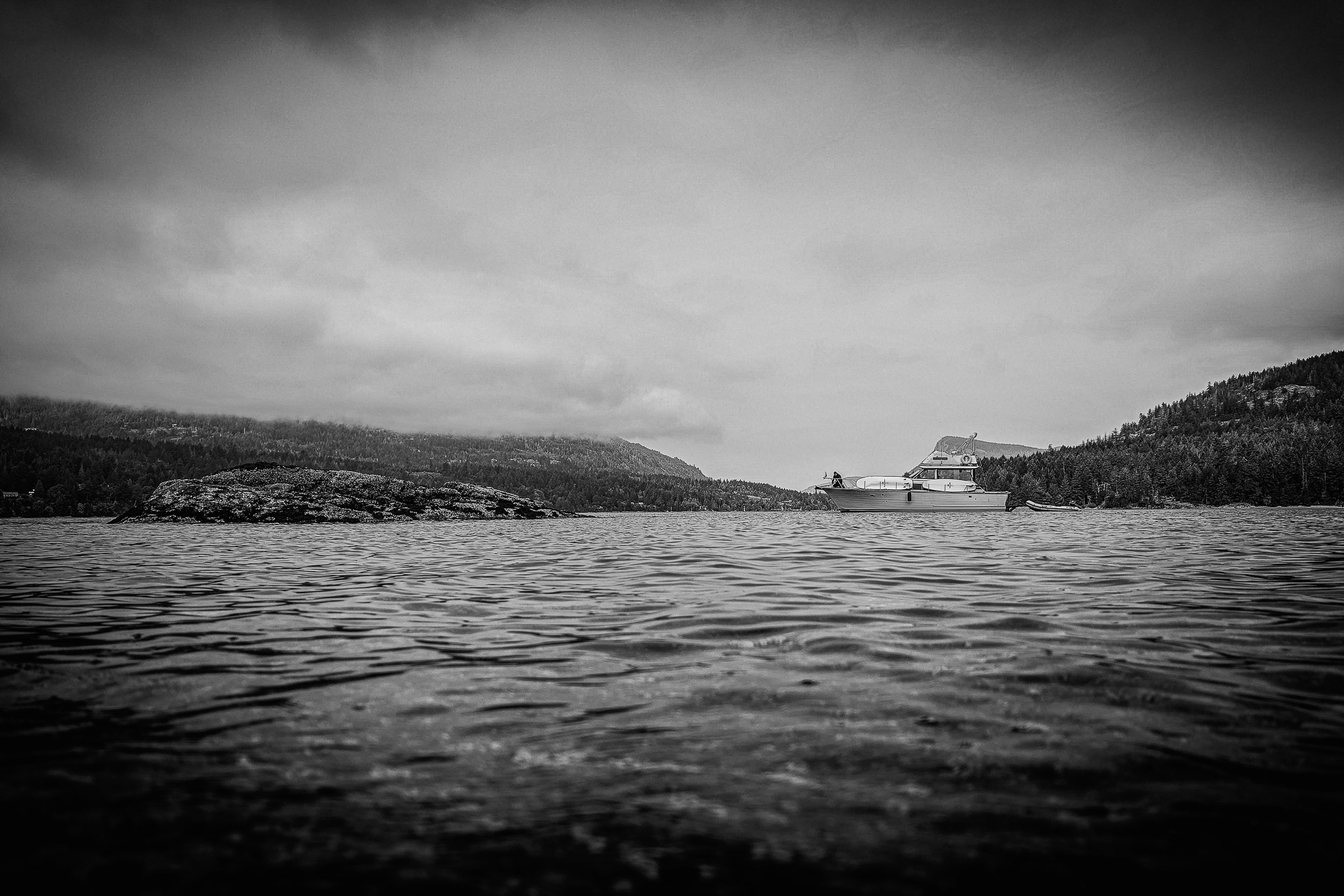 A low dark shoreline divides open water from a pale overcast sky.