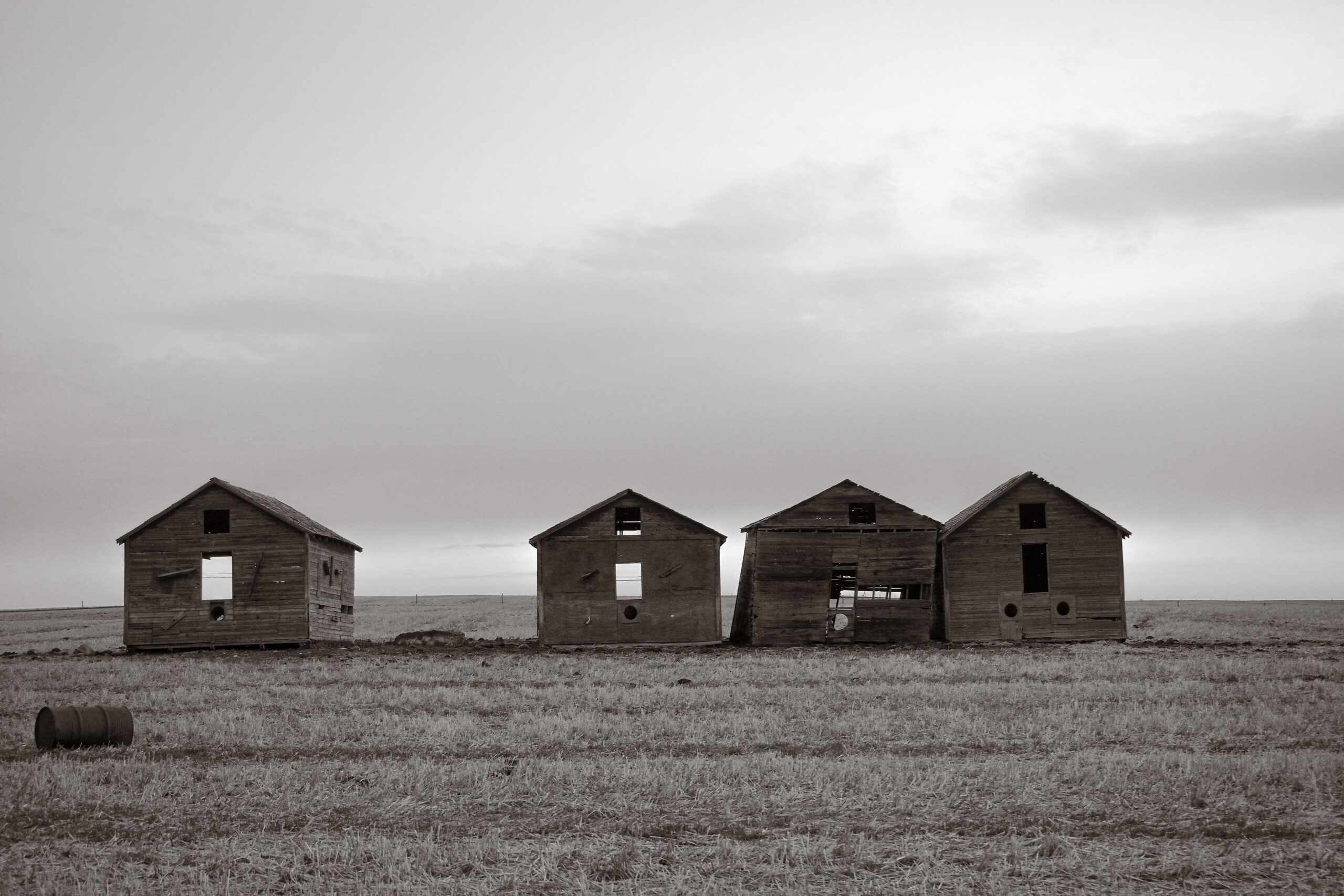 Four small cabins stand in a row across an open field.